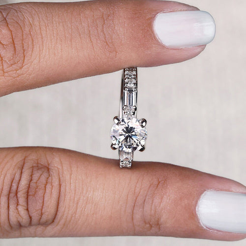 Silver round CZ ring held between fingers side profile view