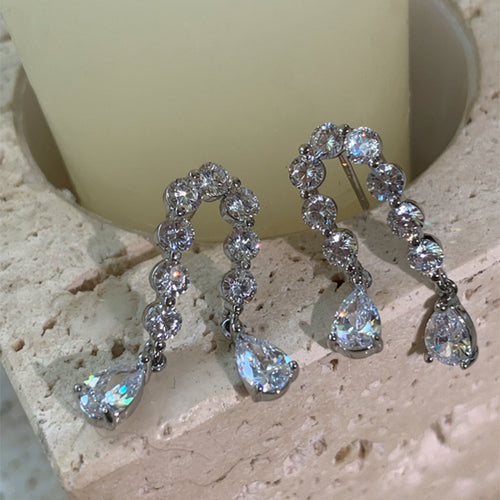 Product close-up of 水晶环形水滴耳夹 showing double rows of clear stones forming loops with faceted teardrop dangles