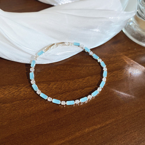 Silver light blue opaque baguette tennis bracelet on wood table white fabric