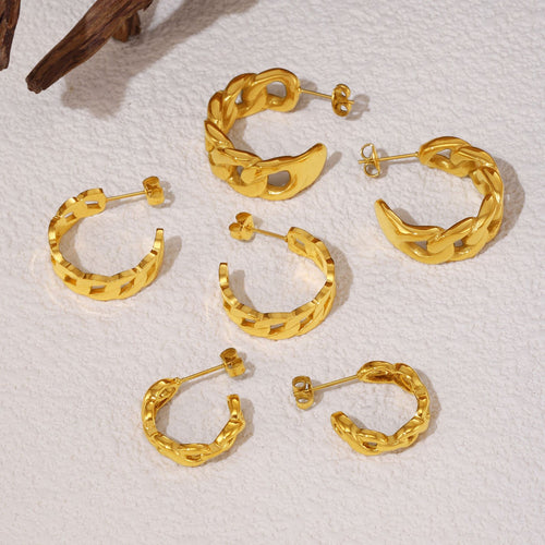 Gold twisted and curb chain C-hoop earrings on white surface