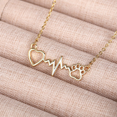 Gold heart heartbeat paw pendant necklace on beige fabric