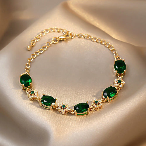 gold-tone bracelet with green oval stones and small flower links in a close product photo