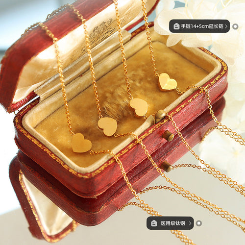 Gold heart bracelets in open red jewelry box with length and material labels