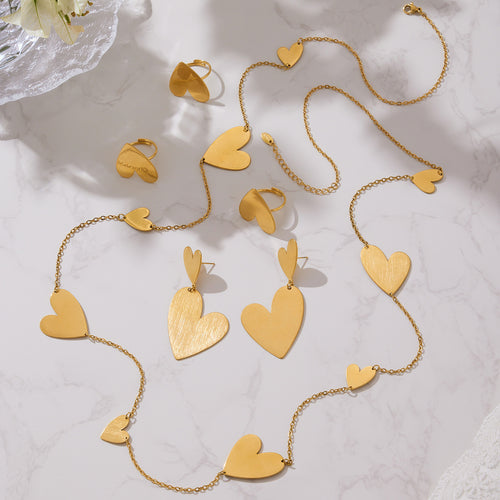 Gold brushed heart rings earrings and multi-heart necklaces on marble