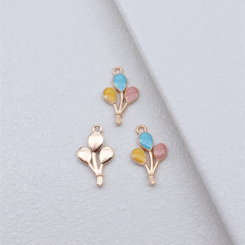 Enamel balloon bouquet charms arranged on a natural wood surface