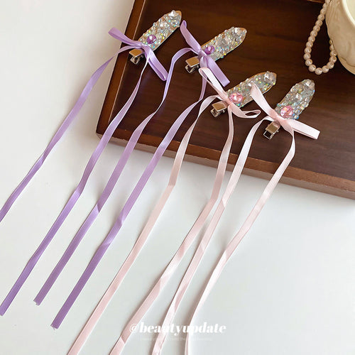Four purple and pink rhinestone ribbon duckbill clips on wood tray
