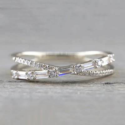 Silver crossed baguette pave split shank ring on wood surface