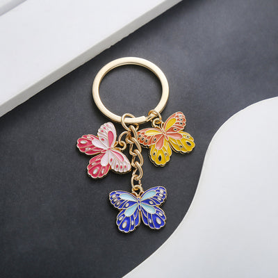 Front product photo of yellow pink and blue butterfly enamel charm keychain showing the pictured design arrangement