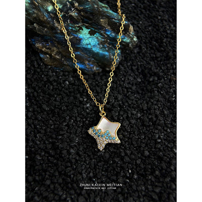 Gold-tone white starfish blue-stone pendant necklace on black textured fabric.