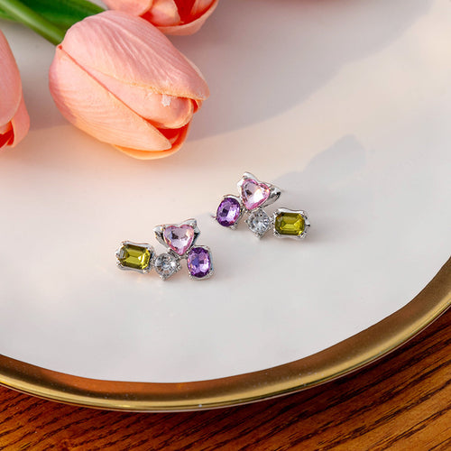 Silver pink purple green gem cluster studs on white plate with tulips