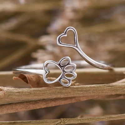 Silver cat paw and heart open ring on dry twigs close-up