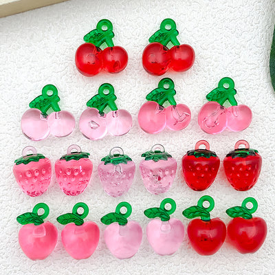 Multicolor cherry and strawberry charms arranged on a light background