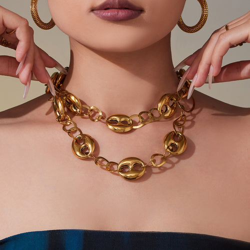 Model wearing layered gold coffee bean link necklaces at collarbone