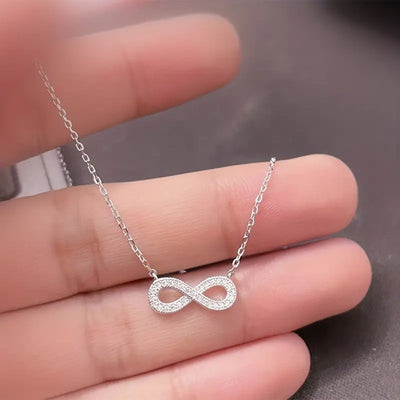 Silver infinity pendant necklace held in open hand
