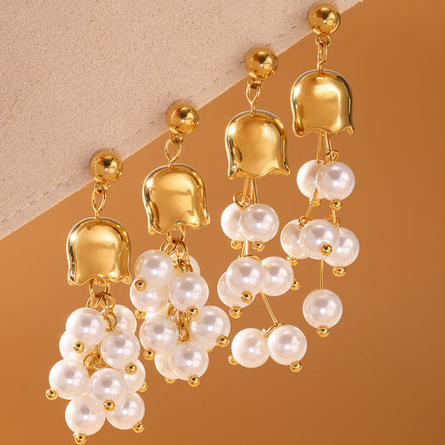 White pearl grape-cluster gold bell earrings on beige fabric