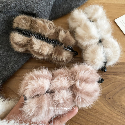 Coffee pink and white faux fur pom ball twist clips on wood table