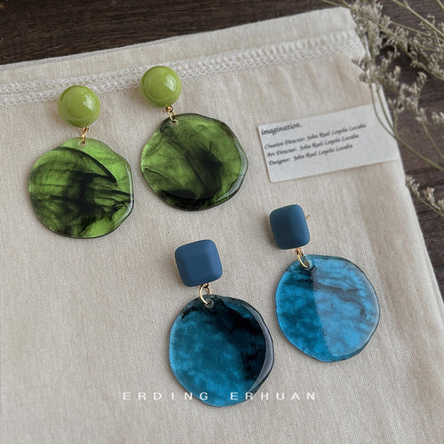 Blue and green mottled-resin disc drop earrings shown as both colors.