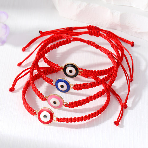 Four red braided evil eye bracelets overlapping on white surface
