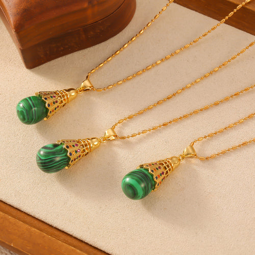 Three gold malachite badminton-style pendants on cream jewelry display