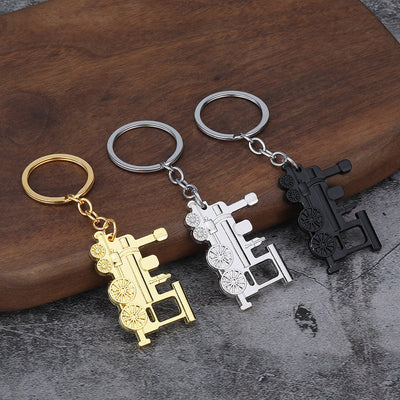 Three steam locomotive keychains in silver, gold, and matte black finishes.
