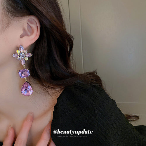 Styled close-up of purple crystal floral drop earrings