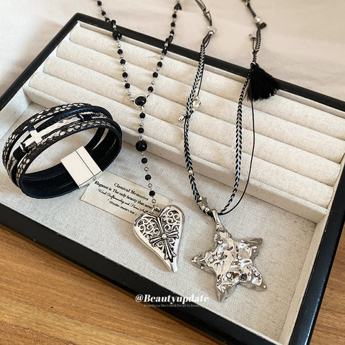 black beaded pendant necklaces with heart and star charms shown in an on-ear styling view