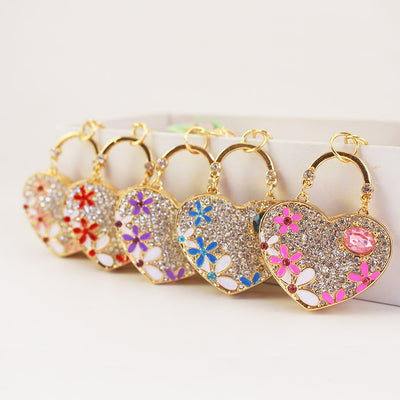 Five gold-tone heart pendants displayed in pink, blue, purple, red, and peach floral designs.