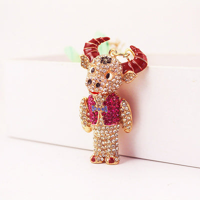Front three-quarter view of the rhinestone bull figure with red horns and a red vest.