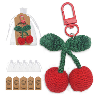 Crocheted cherry keychain displayed beside a white drawstring bag and brown tags.