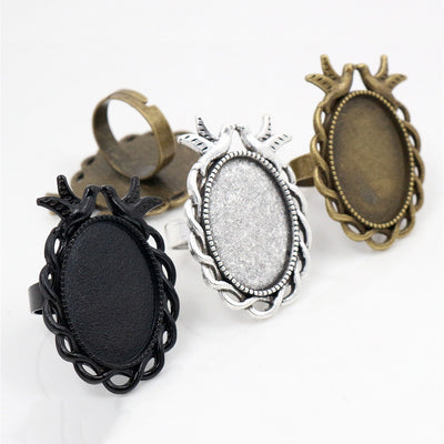 Overview of ornate oval adjustable ring settings with bird and scroll frame details on a light background
