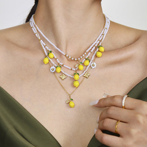 Model wearing layered lemon pearl and gold chain necklaces