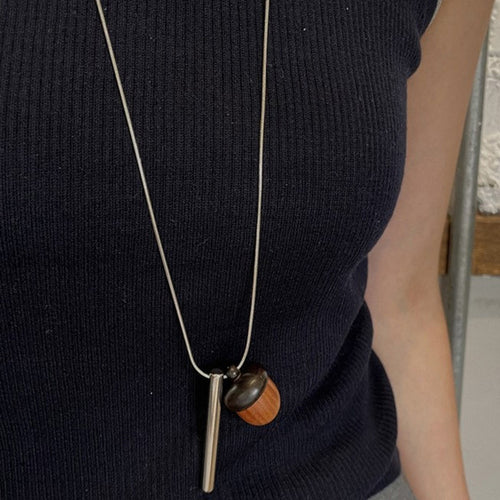 A long silver-tone chain with a brown wood-look acorn and slim bar drops, styled view