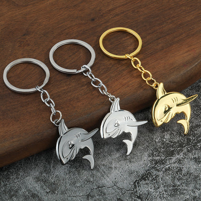Three shark keychains in silver, gunmetal and gold finishes