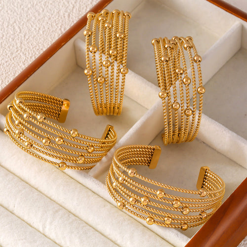 Four gold twisted rope bead open cuffs in jewelry display tray