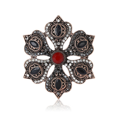 Front view of antique tone floral medallion brooch with red center