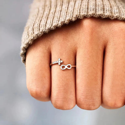 Silver open infinity cross CZ ring worn on fist with knit cuff