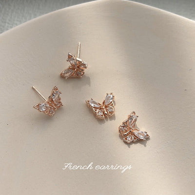 Four rose gold clear crystal butterfly studs scattered on beige dish