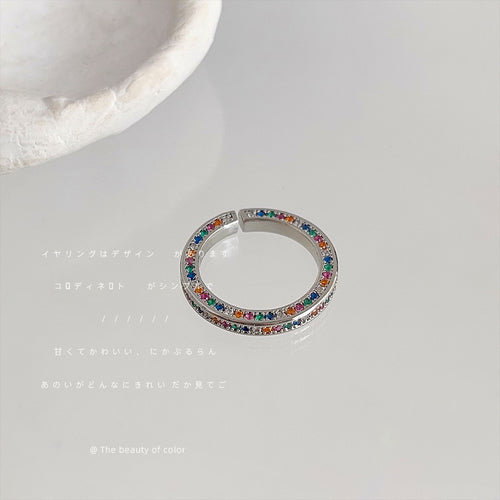 Silver multicolor pavé open ring on white surface near ceramic prop