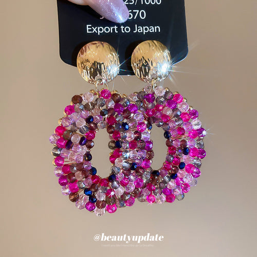 Open oval drops set with bright pink and clear crystals shown in a styled close-up