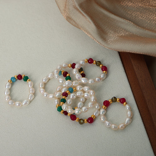 Pile of pearl stretch rings with colored faceted beads on fabric
