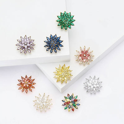 Front view of layered crystal snowflake brooch against a white background.