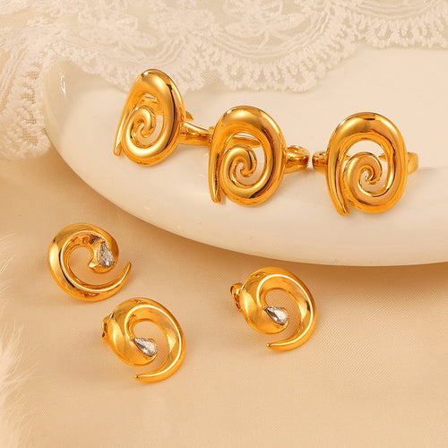 Three gold spiral rings and three teardrop-stone studs on tray