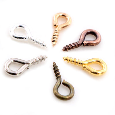 Front overview of small screw eye pins in mixed metal and bright colors arranged on a light background
