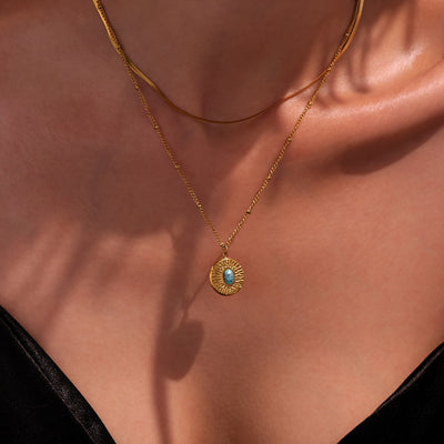 Gold turquoise sunburst pendant necklace worn layered on collarbone