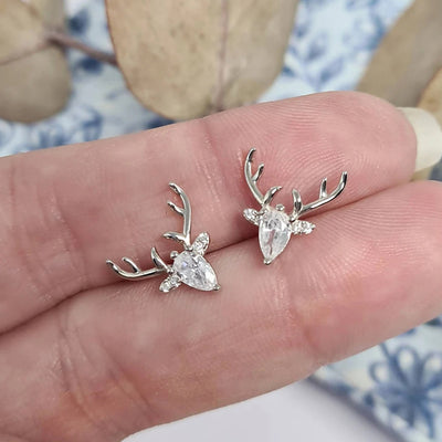 Silver deer head stud earrings with clear stones held in hand