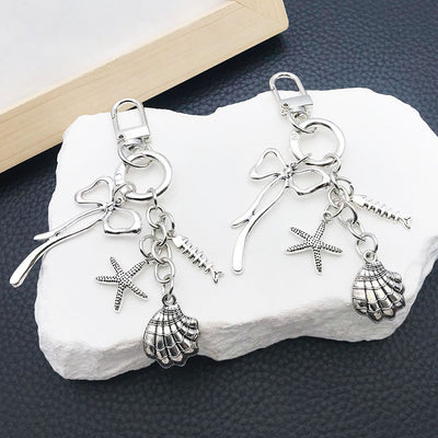 Main display of three silver tone bow shell and starfish clasp keychains