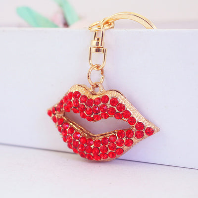 Angled front view of a red rhinestone lips charm attached to a gold-tone key ring.