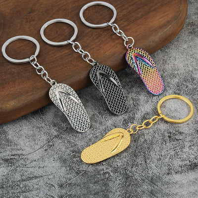 Four textured flip-flop keychains displayed in silver, gunmetal, gold and rainbow finishes.