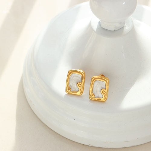 Pair of gold white enamel scroll studs on white ceramic