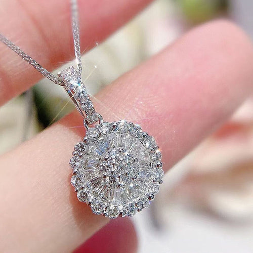 Round flower crystal halo pendant held on fingertips soft blur background